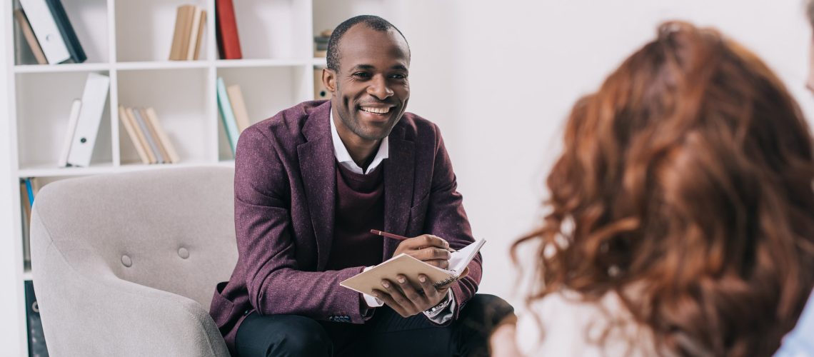 Smiling african american psychiatrist talking to young couple