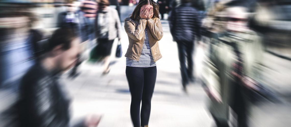 Panic attack in public place. Woman having panic disorder in city. Psychology, solitude, fear or mental health problems concept. Depressed sad person surrounded by people walking in busy street.