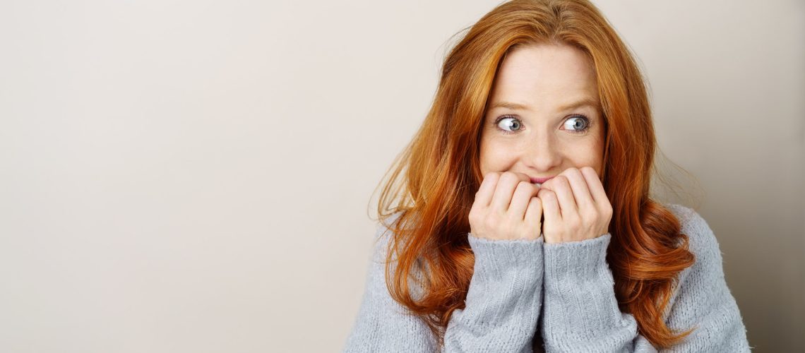 frau blickt angespannt zur seite und hält die hände vor den mund