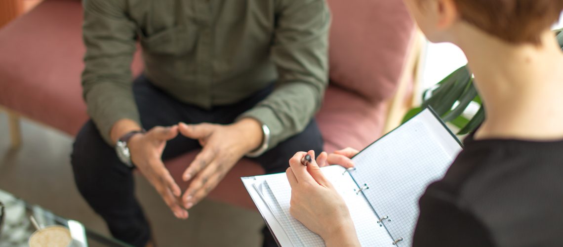 psychotherapist consulting man, asking questions, interviewing man sitting on sofa. psychologist with client