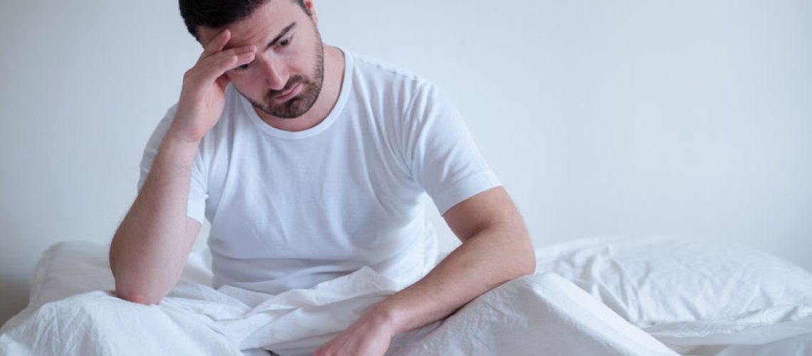 Sad and upset man waking up in the morning light